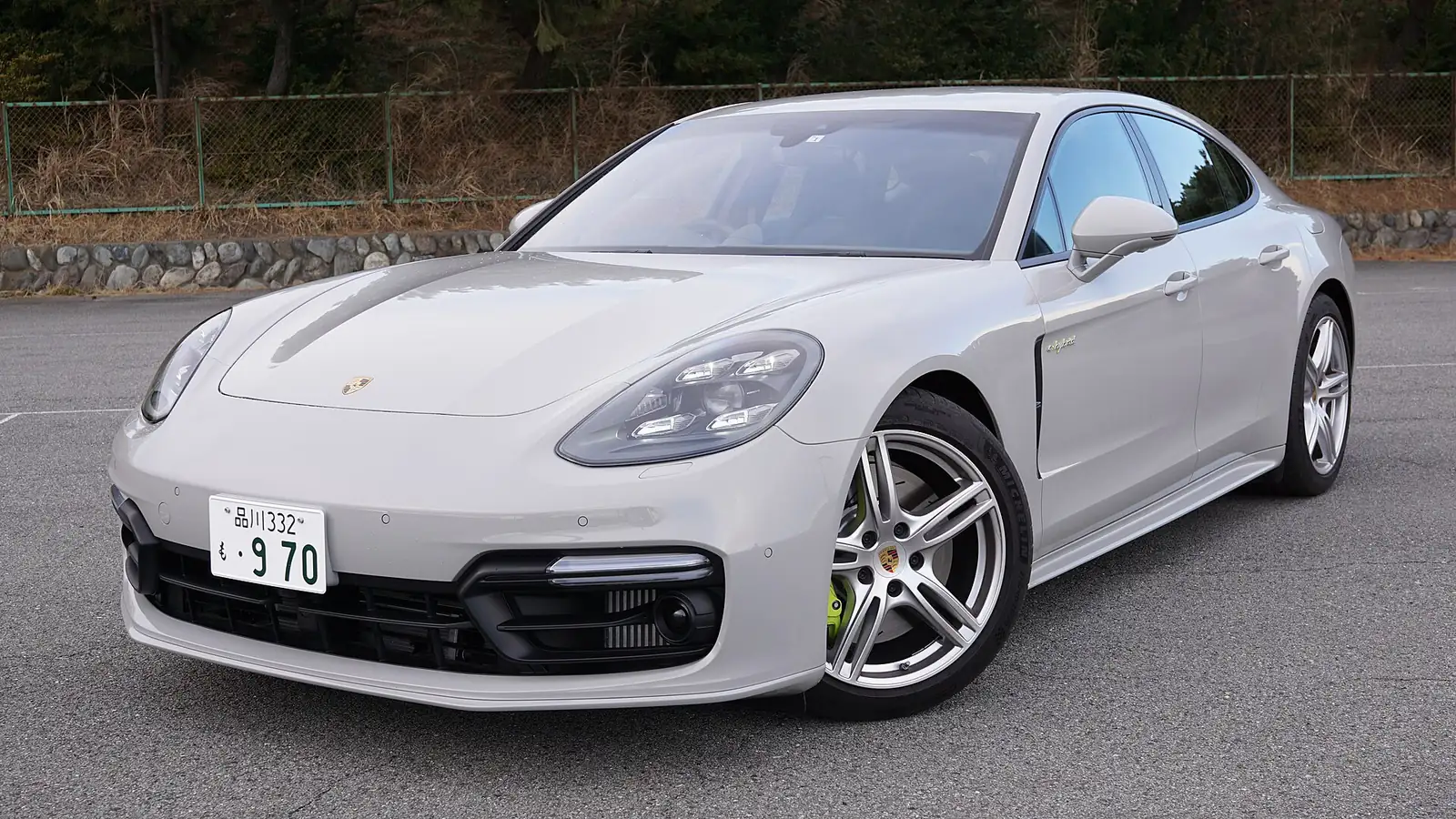 Silver Porsche Panamera 4 E-Hybrid liftback photographed from the front three-quarter angle in a car park, with green brake calipers denoting the hybrid powertrain