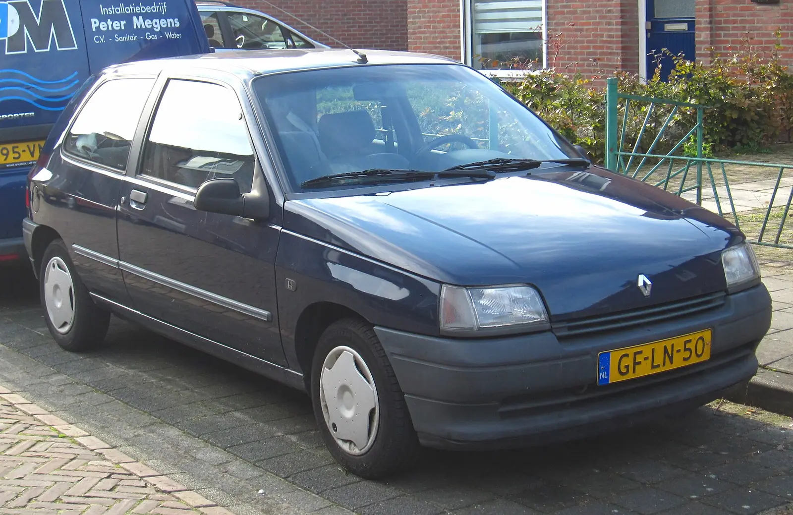 Dark blue first-generation Renault Clio parked kerbside, photographed from the front three-quarter angle