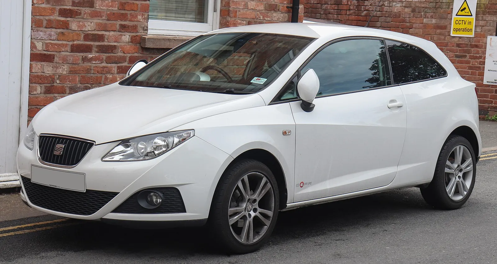 White fourth-generation SEAT Ibiza three-door hatchback photographed from the front three-quarter angle outside a brick building