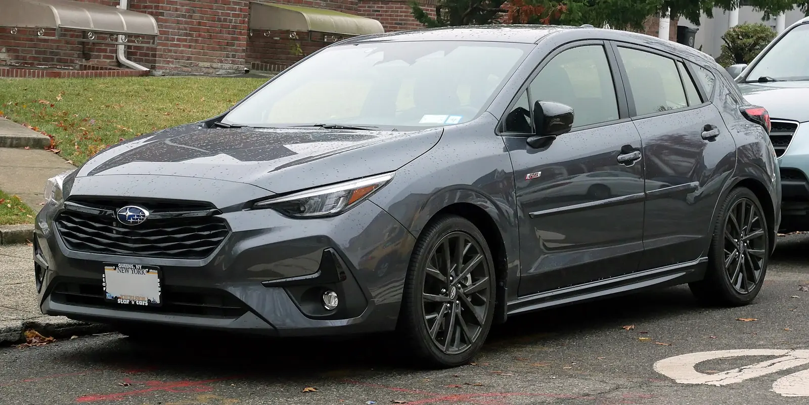Grey current-generation Subaru Impreza RS hatchback photographed from the front three-quarter angle in the rain