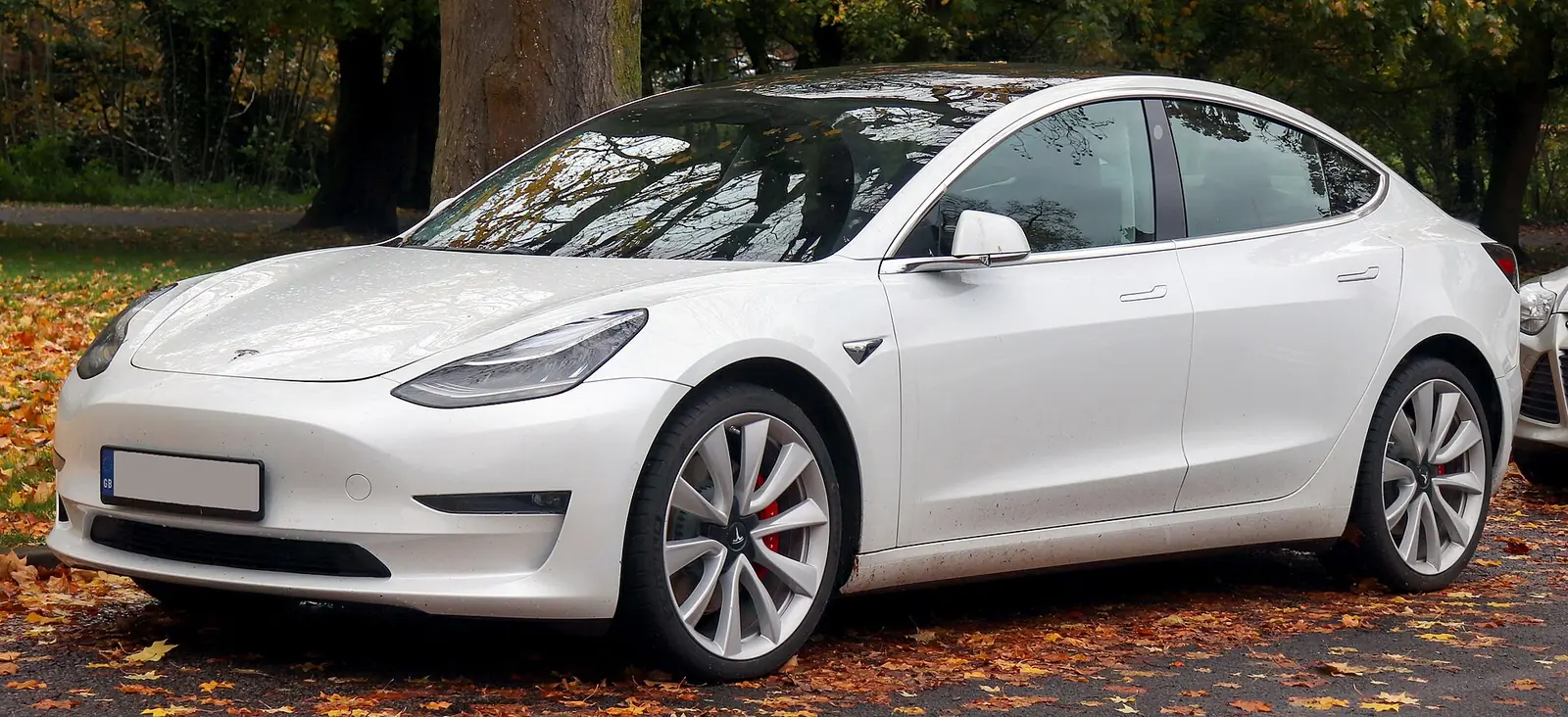 Red Tesla Model 3 Performance photographed from the front three-quarter angle, showing the grille-less nose and flush door handles