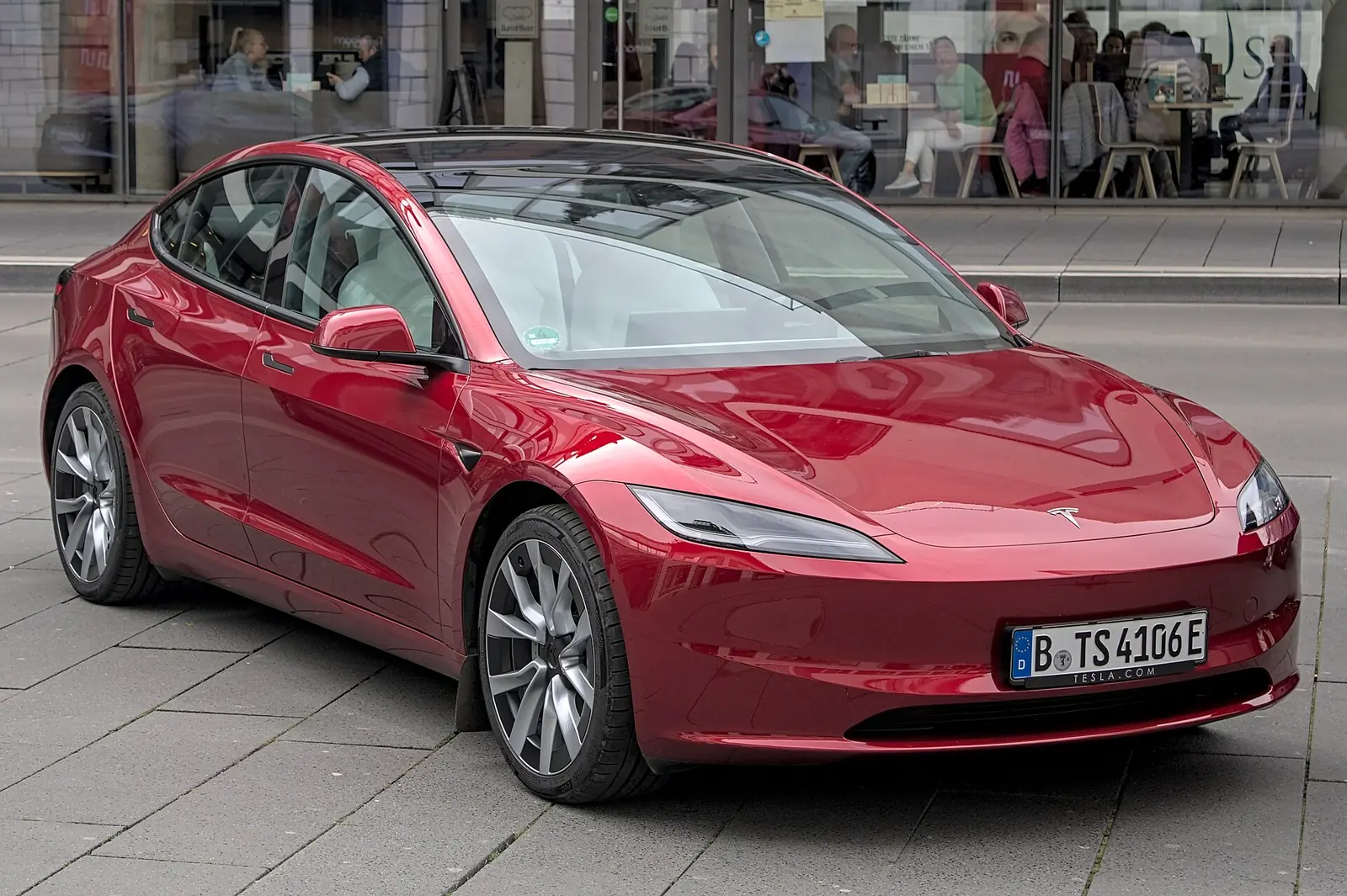 White Tesla Model 3 of the 2023 facelift photographed from the front three-quarter angle, showing the narrowed headlamps and smoothed nose