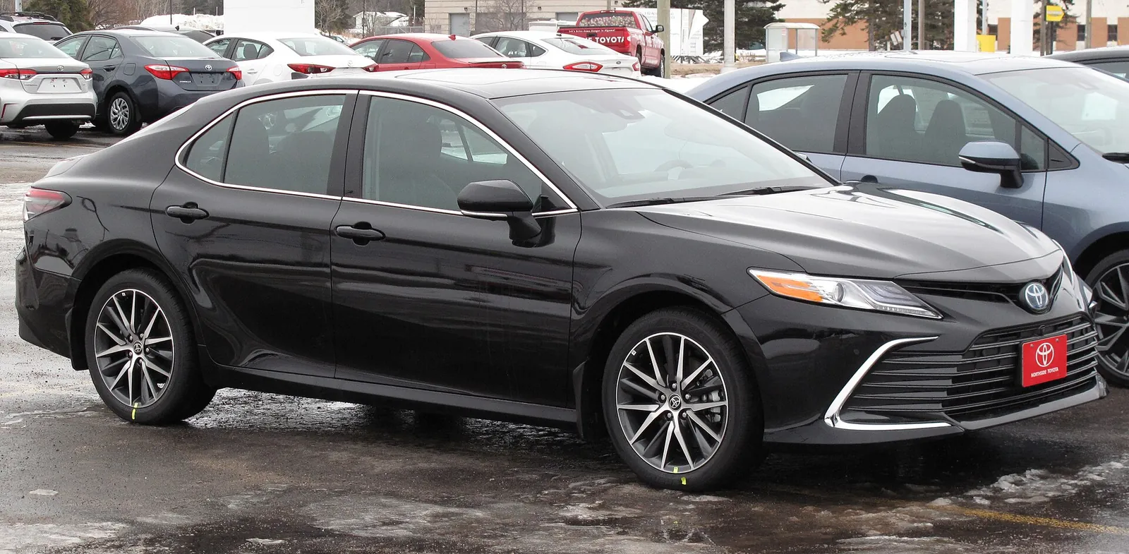 Black 2022 Toyota Camry Hybrid XLE saloon photographed from the front three-quarter angle in a car park