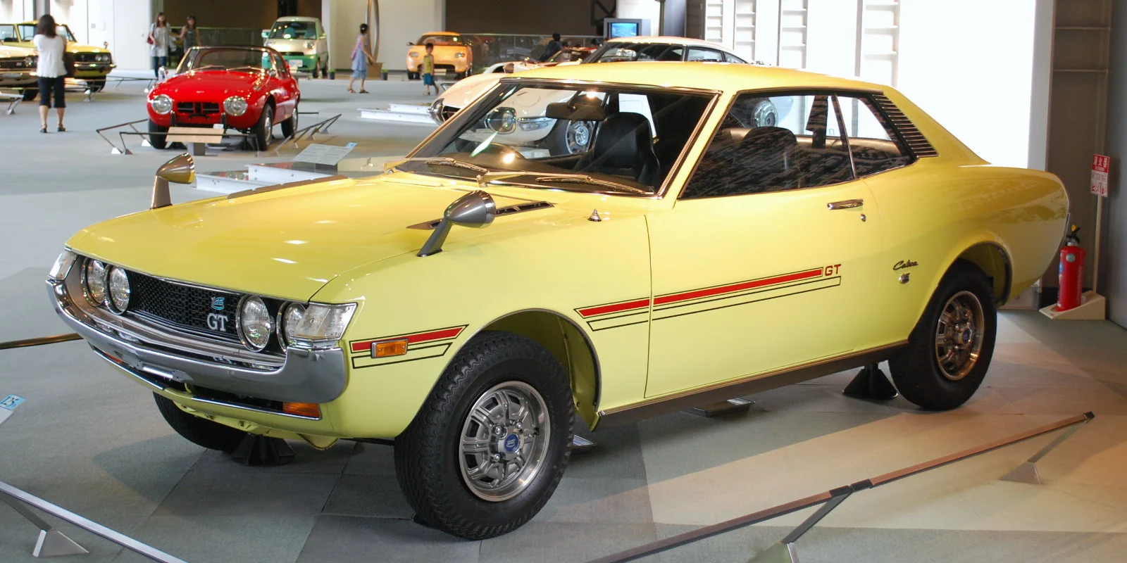 Yellow original Toyota Celica coupé photographed from the front three-quarter angle