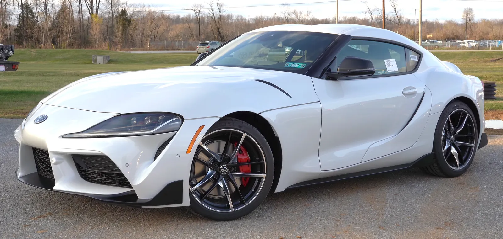 White Toyota GR Supra photographed from the front three-quarter angle, showing its double-bubble roof and vented front fenders