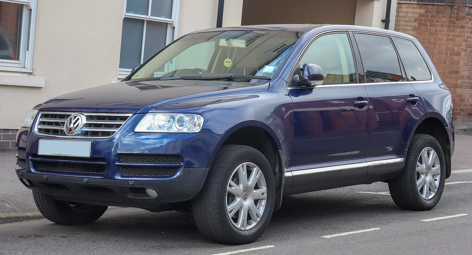Dark blue first-generation Volkswagen Touareg SUV photographed from the front three-quarter angle outside a house