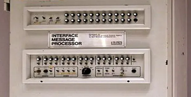 A cream-coloured metal equipment panel labelled INTERFACE MESSAGE PROCESSOR, fitted with two rows of illuminated push-buttons and switches, mounted inside an open cabinet.