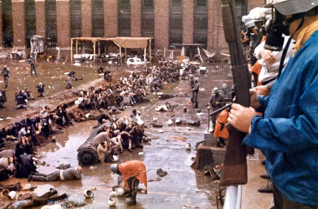 State troopers in gas masks stand over rows of prisoners lying face down in the mud of a prison yard, after retaking a New York correctional facility by force.