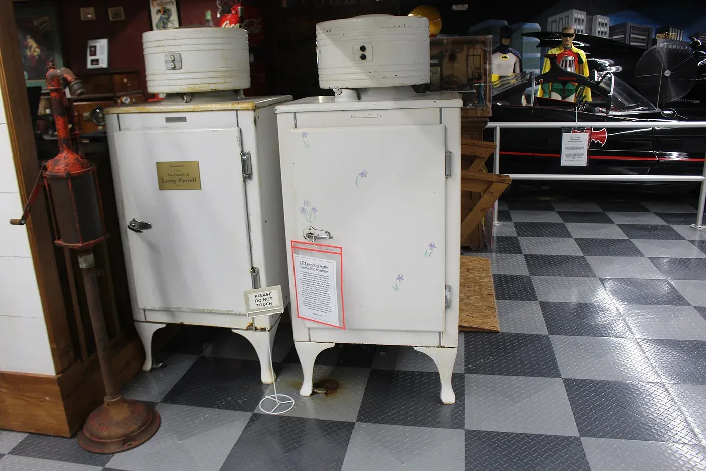 Two General Electric Monitor-Top refrigerators on display, tall white enameled steel cabinets with a rounded compressor housing on top and cabriole legs.