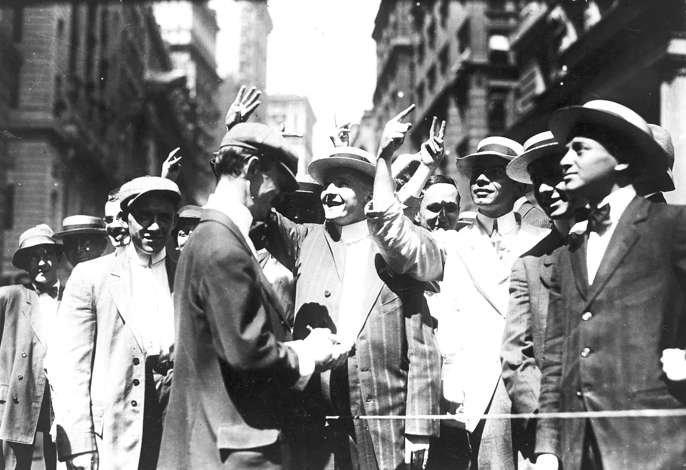 Crowds of brokers packed into a New York street, signalling with their hands up to clerks leaning from the office windows above.