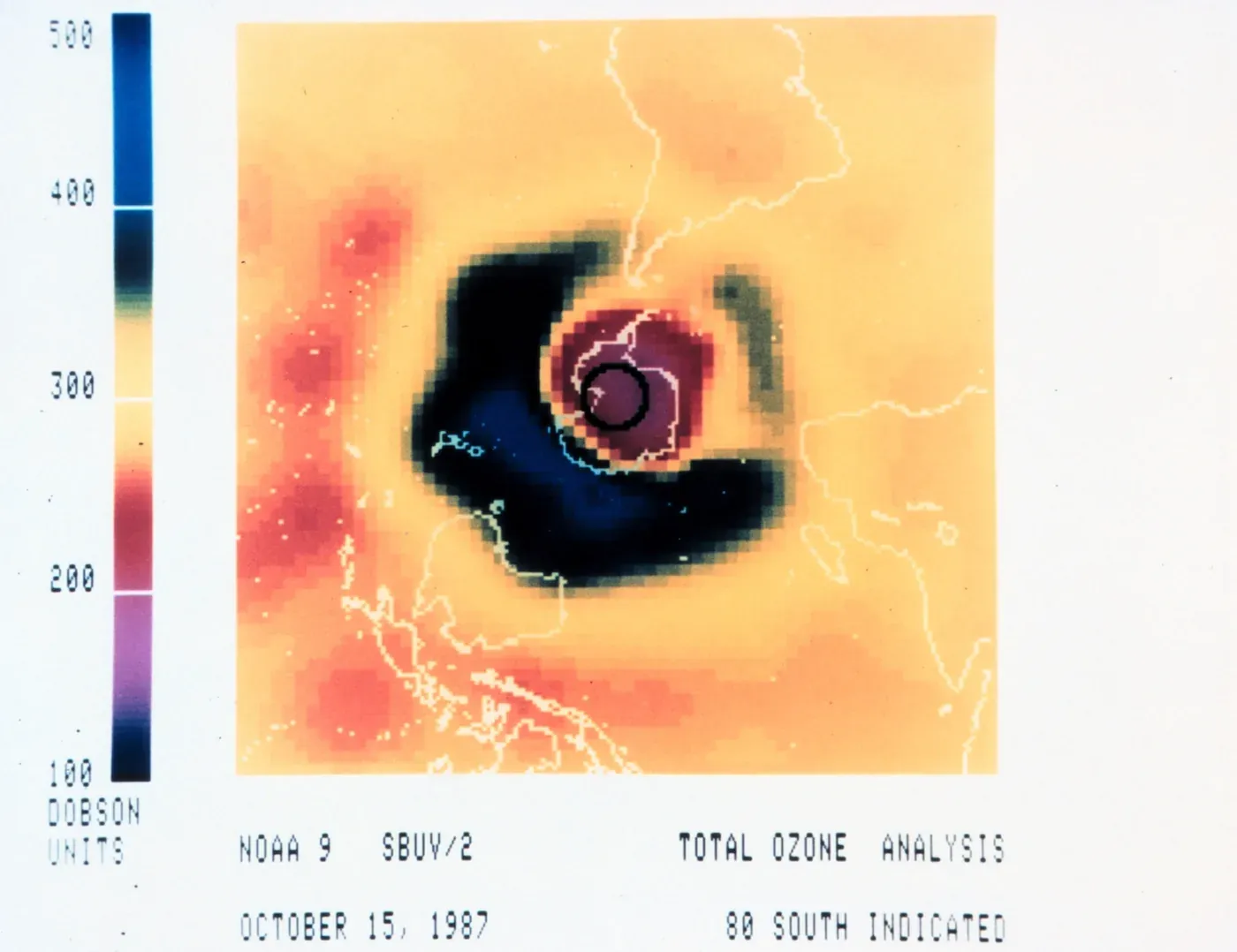 A false-color satellite map centered on Antarctica, with a large dark blue and black region over the pole surrounded by concentric bands of orange, red, and yellow representing higher ozone concentrations, dated 15 October 1987.