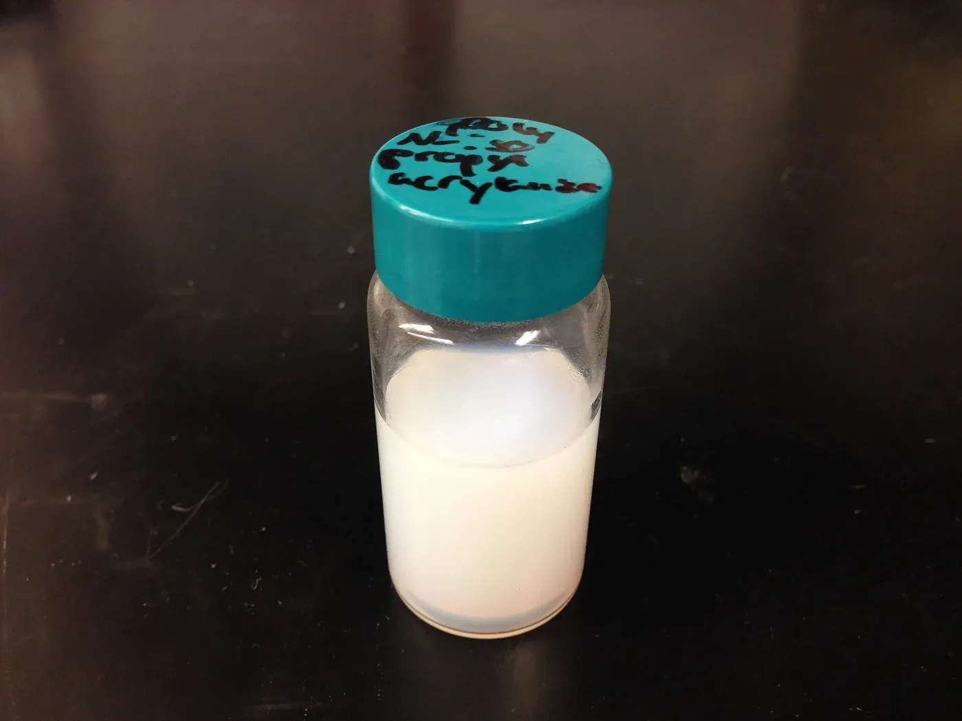 The same style of glass sample vial, now containing a cloudy, opaque white liquid after heating.