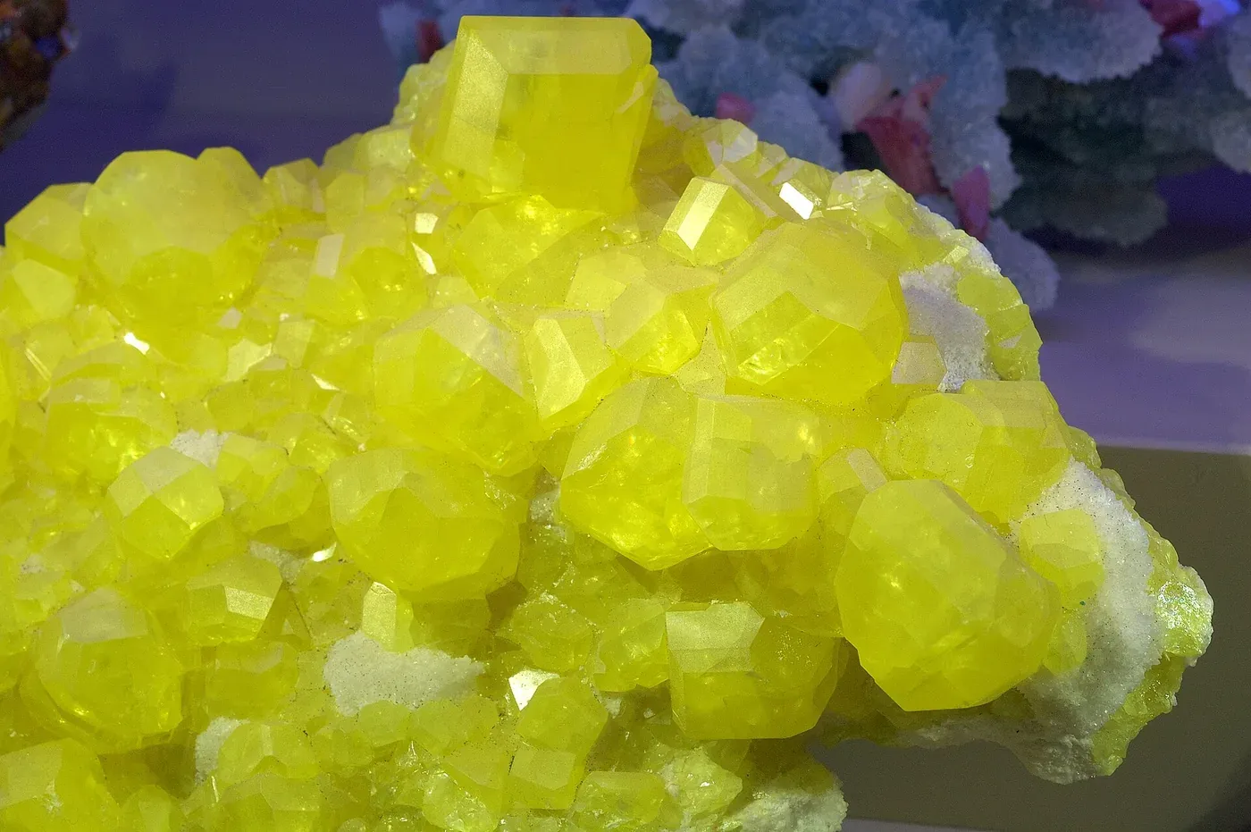 A cluster of translucent, deep yellow crystalline mineral fragments against a dark background.
