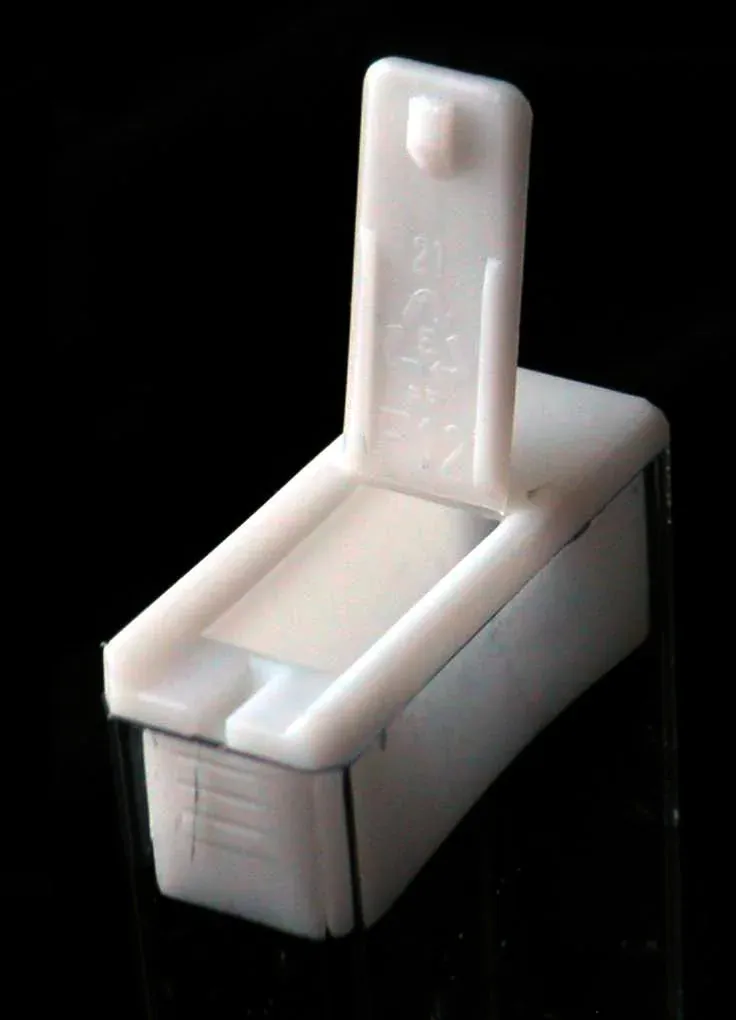 An open white plastic mint box, photographed against a black background, showing its thin moulded lid folded back on a single integral hinge.