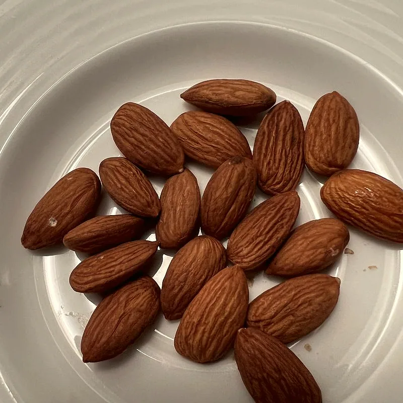 A pile of whole raw almonds on a plate