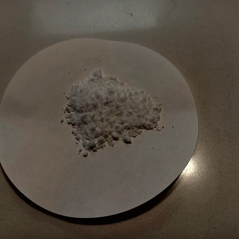 A small pile of white crystalline ammonium bicarbonate powder on a filter paper