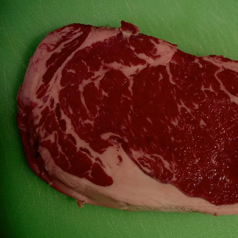 A raw, marbled beef steak on a cutting board