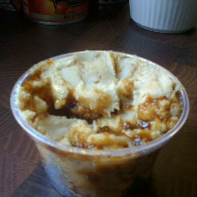 A tub of solidified beef dripping, pale fat with dark meat juices settled at the bottom