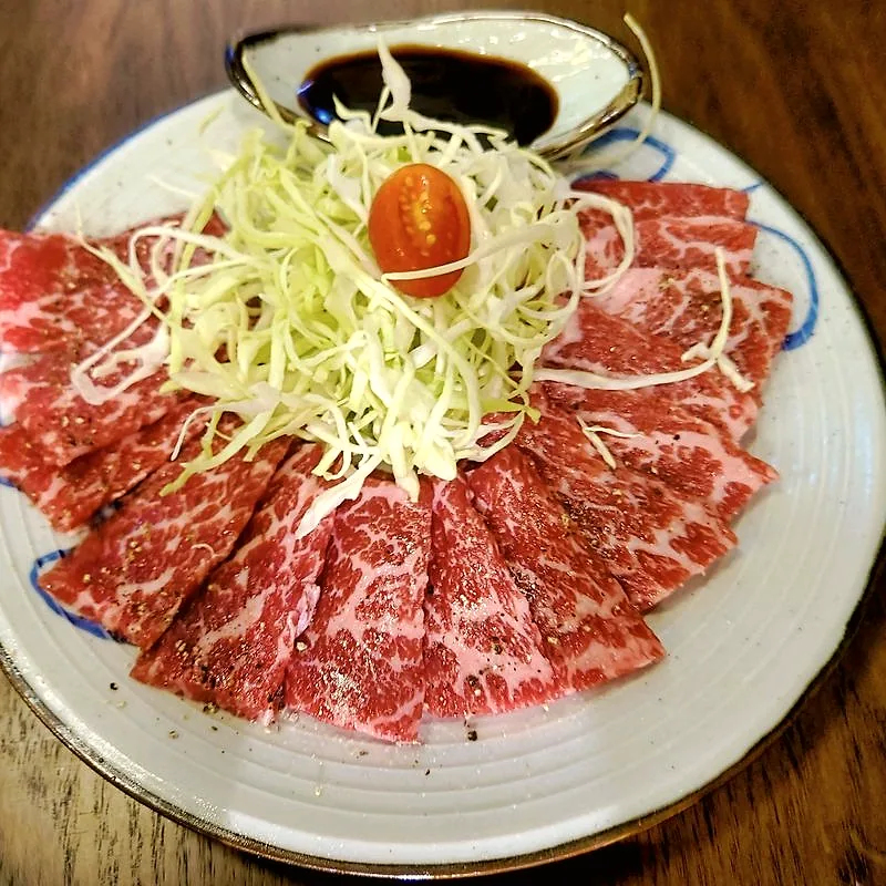 Thin, marbled slices of raw beef short rib fanned out on a plate
