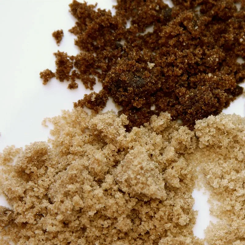 Dark muscovado above light soft brown sugar, both damp and finely crystalline