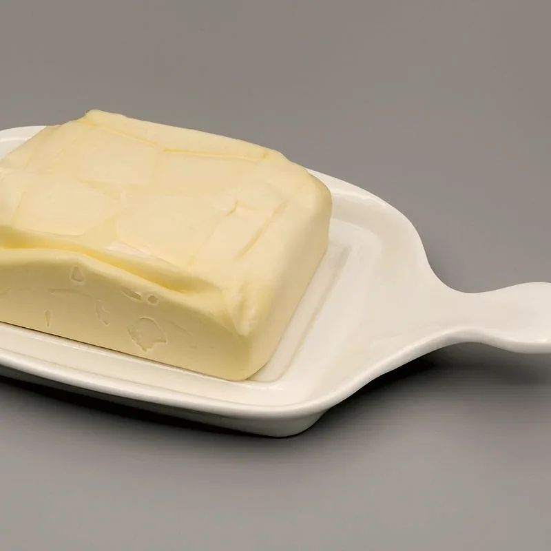 A block of pale yellow butter in a white dish