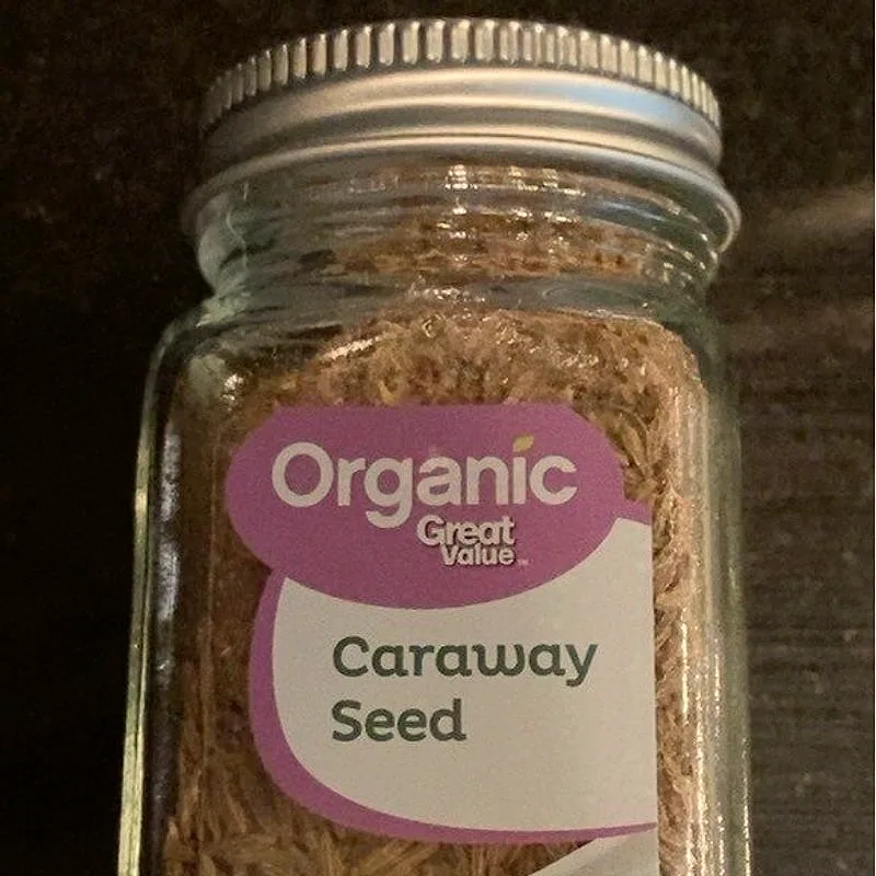 A glass jar of whole caraway seed, the seeds visible through the glass behind the label