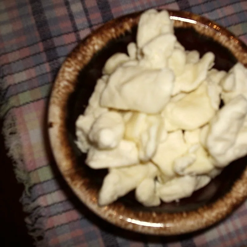 A bowl of fresh, irregular-shaped pale yellow cheese curds