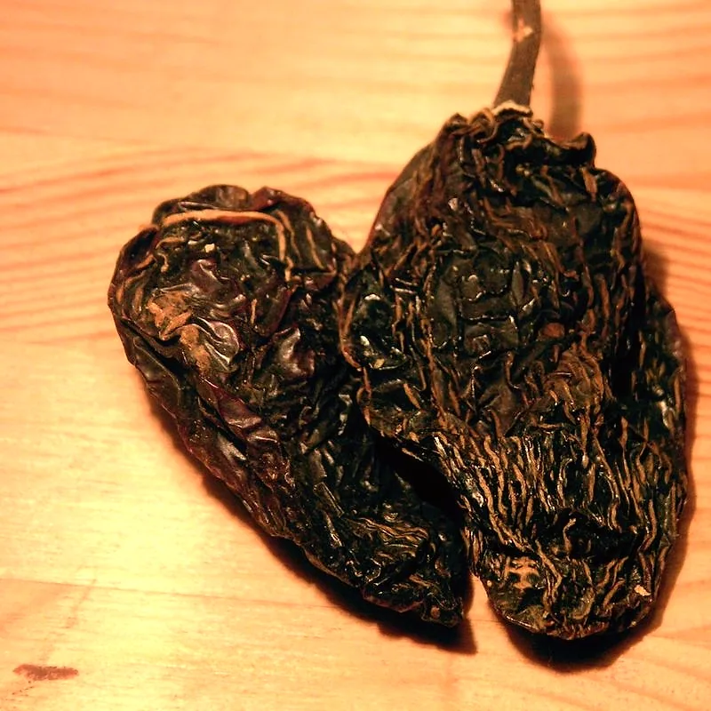 Two wrinkled, dark brown dried chipotle chillies