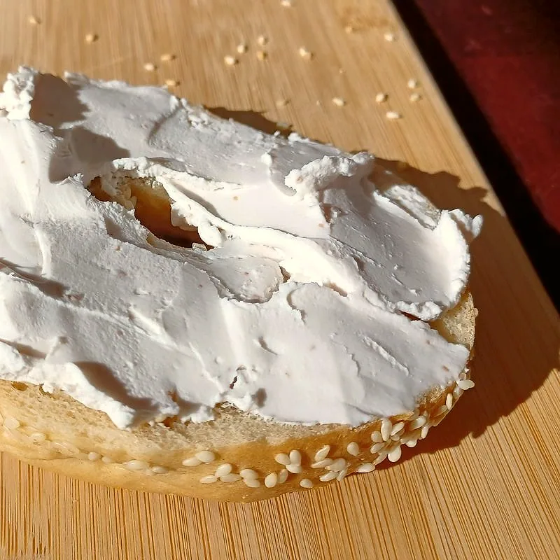 Cream cheese spread thickly on a sesame bagel half
