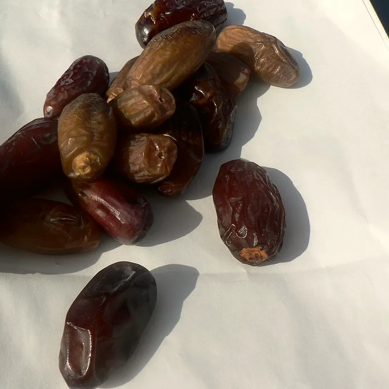 A small pile of dried dates, dark brown and wrinkled