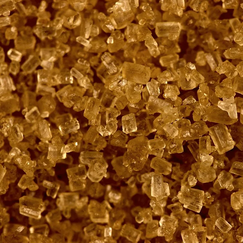 A close view of demerara sugar, large golden-brown sugar crystals