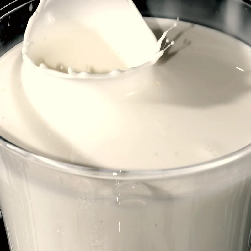 Thick liquid cream in a clear container, with a splash where a spoonful has just been lifted from the surface