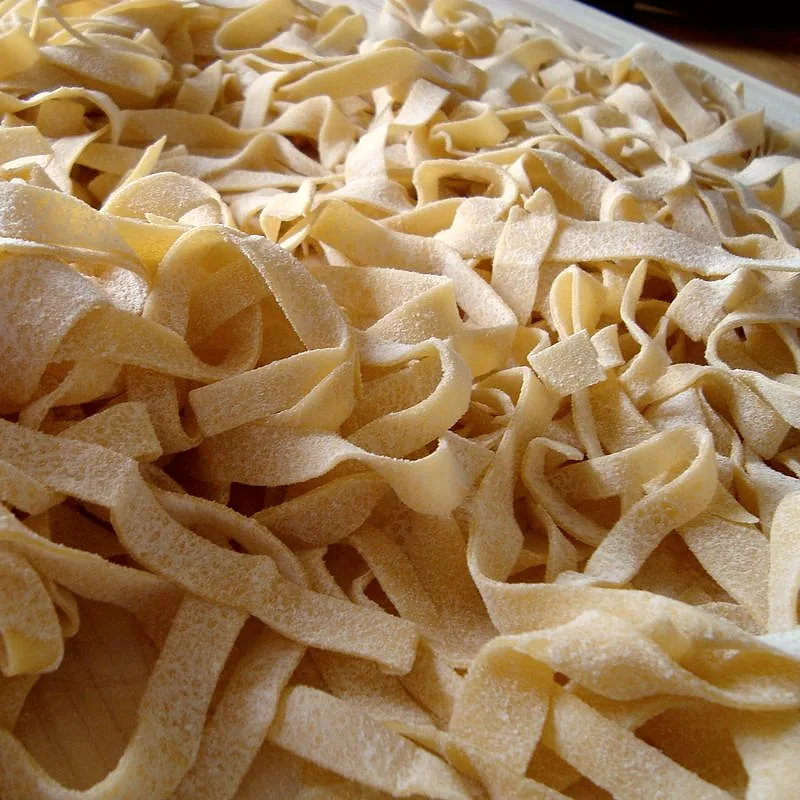 A pile of raw, dried fettuccine ribbon pasta