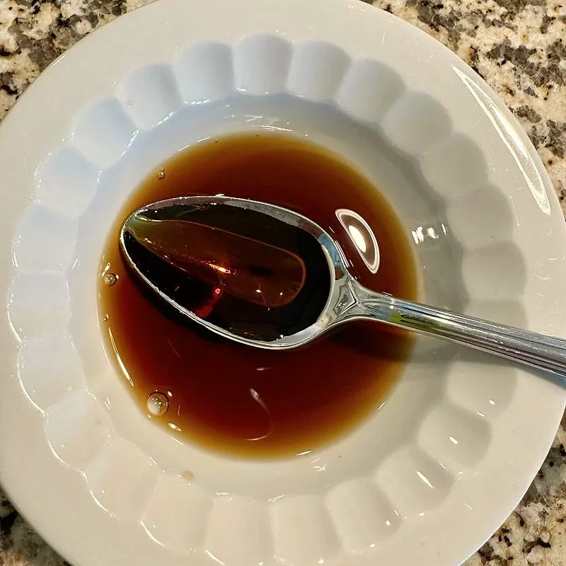 A shallow dish of amber fish sauce with a spoon resting in it