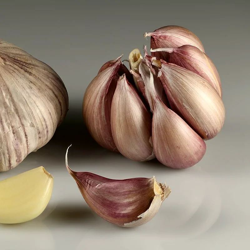 Whole garlic bulbs beside a separated clove
