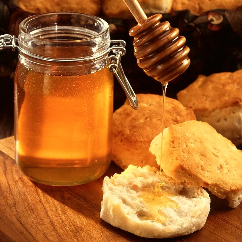 Golden honey in a jar, drizzling from a honey dipper