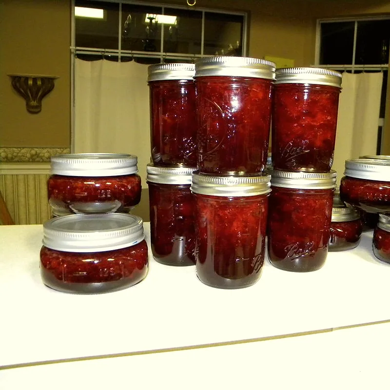 Jars of deep red homemade strawberry jam, freshly filled and sealed