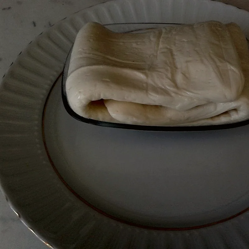 A folded block of white, stringy dil peyniri cheese on a plate
