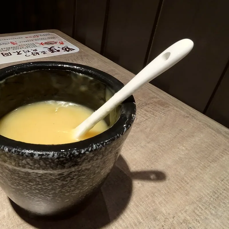 A small bowl of melted lard, a pale golden rendered pork fat, with a spoon