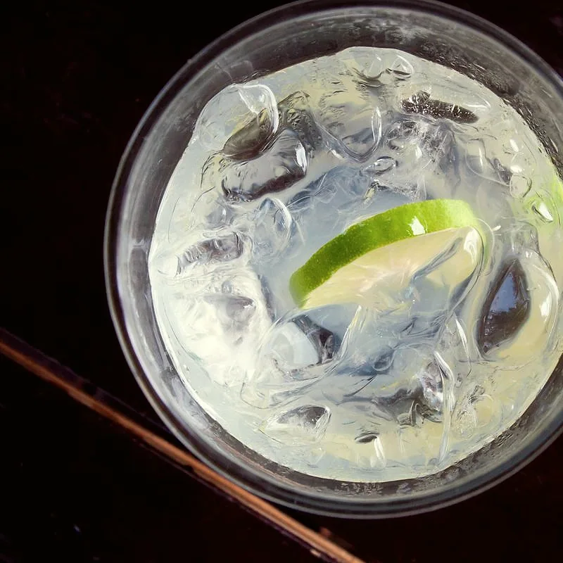 A tall glass of cloudy lime juice over ice with a slice of lime