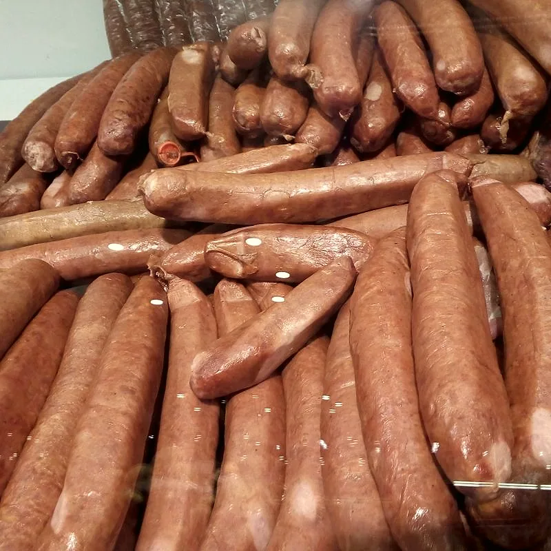 A pile of linguiça sausages, reddish-brown smoked pork links in natural casing