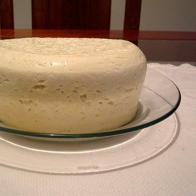 A whole round of fresh minas cheese, pale white with a slightly rough surface