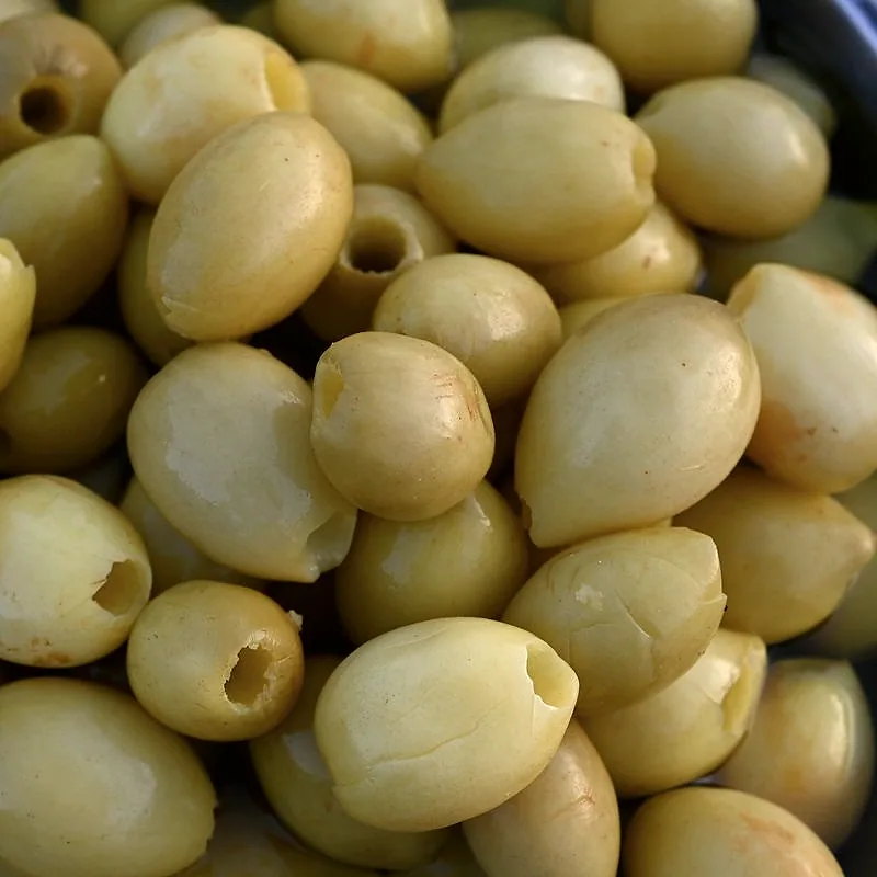 A close pile of pitted green olives with smooth, glossy skins