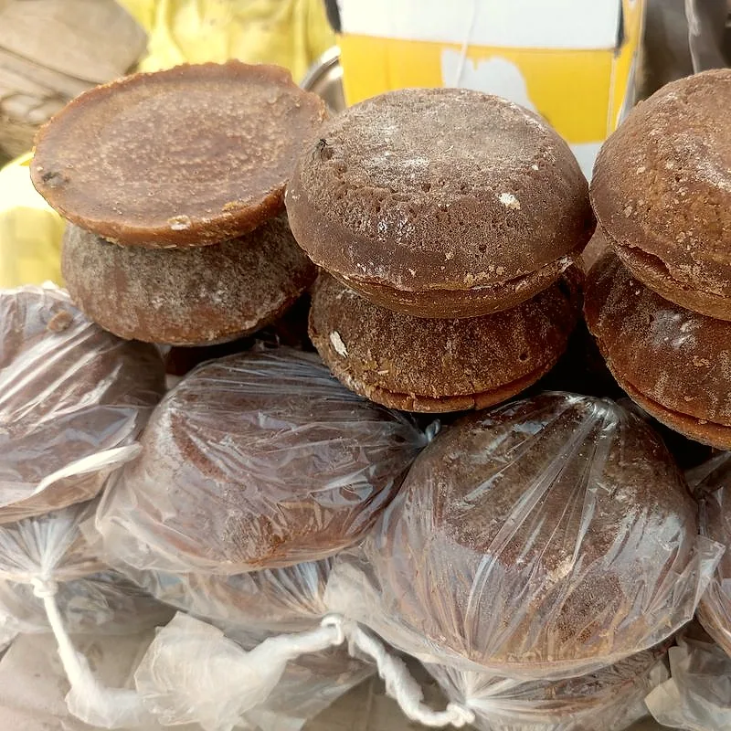 Stacked cylindrical blocks of dark palm sugar at a market stall