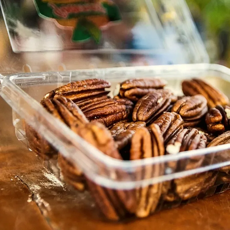 A plastic punnet piled with shelled pecan halves, showing their ridged brown shells and pale flesh