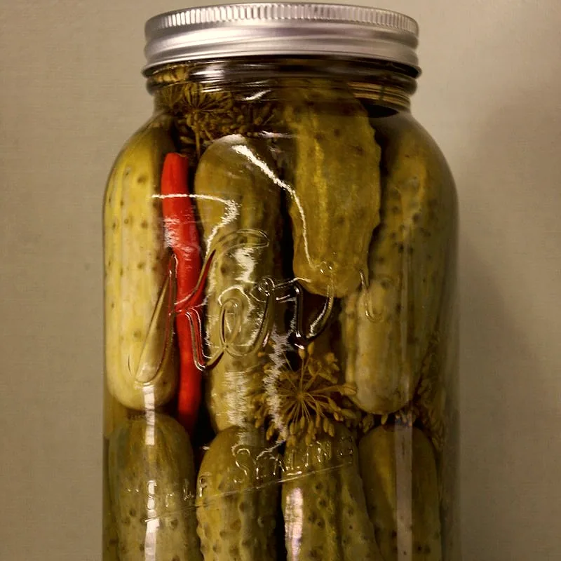 Two halved dill pickle spears showing their pale green interior and seeds