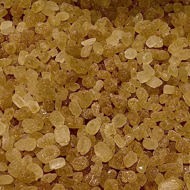 A close-up pile of amber-yellow translucent rock sugar crystals