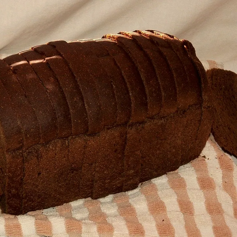 A sliced loaf of dark rye bread on a cloth