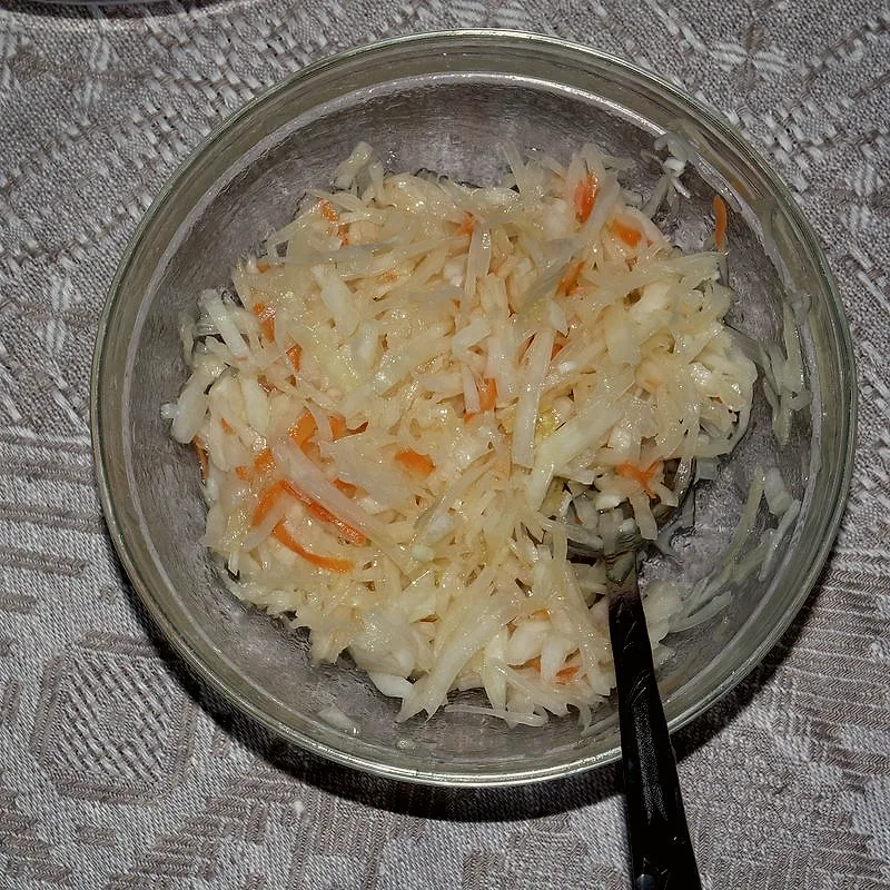 A bowl of sauerkraut with shredded carrot