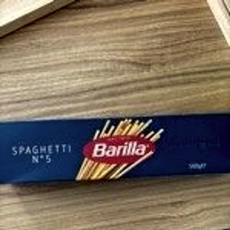 A boxed pack of dried spaghetti lying on a wooden board